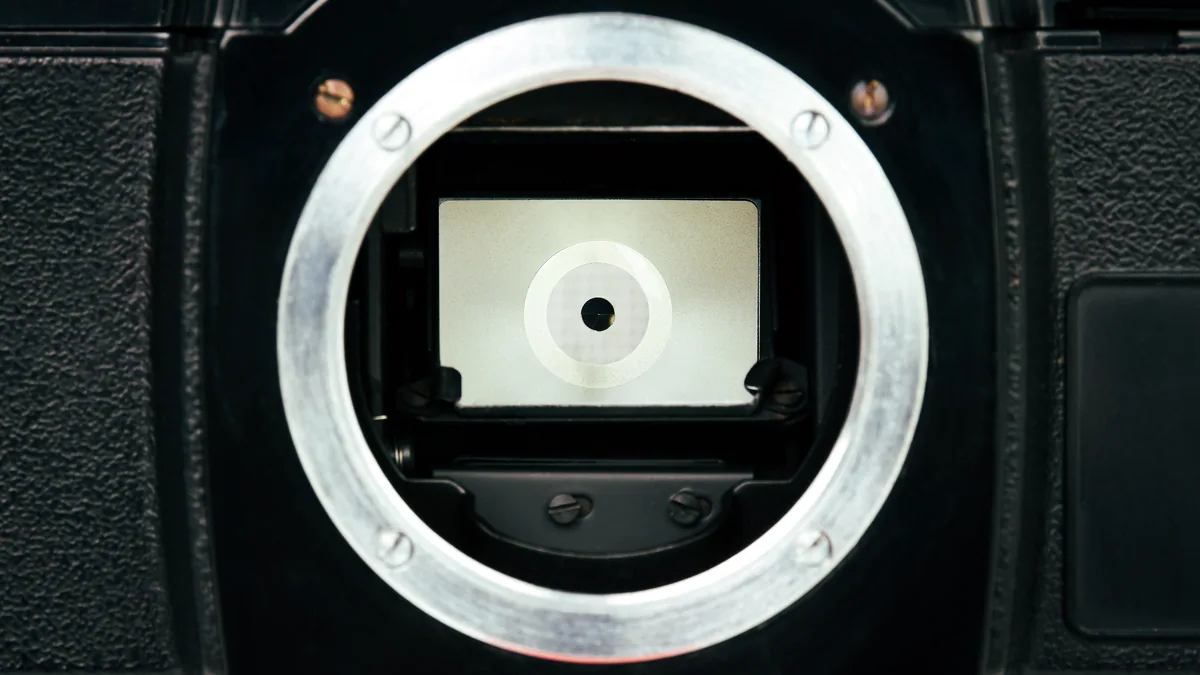 A vintage 35mm camera on a table, its glass lens catching the light.