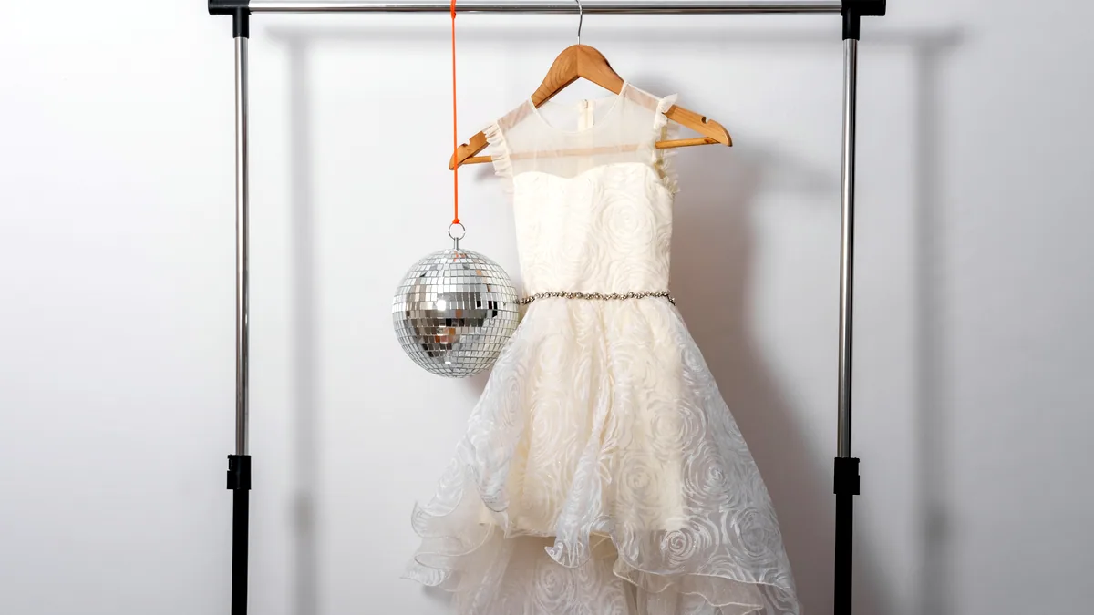 A rail of vintage dresses under warm dressing room lights.