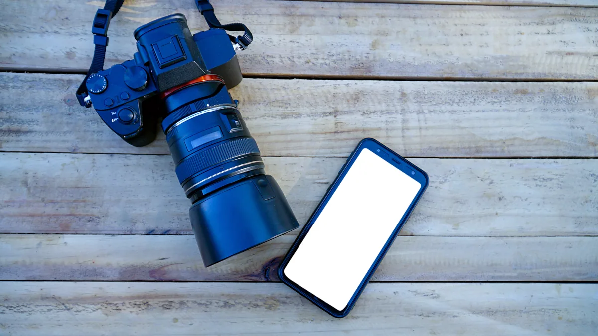 A vintage 35mm camera set beside a glowing phone screen.