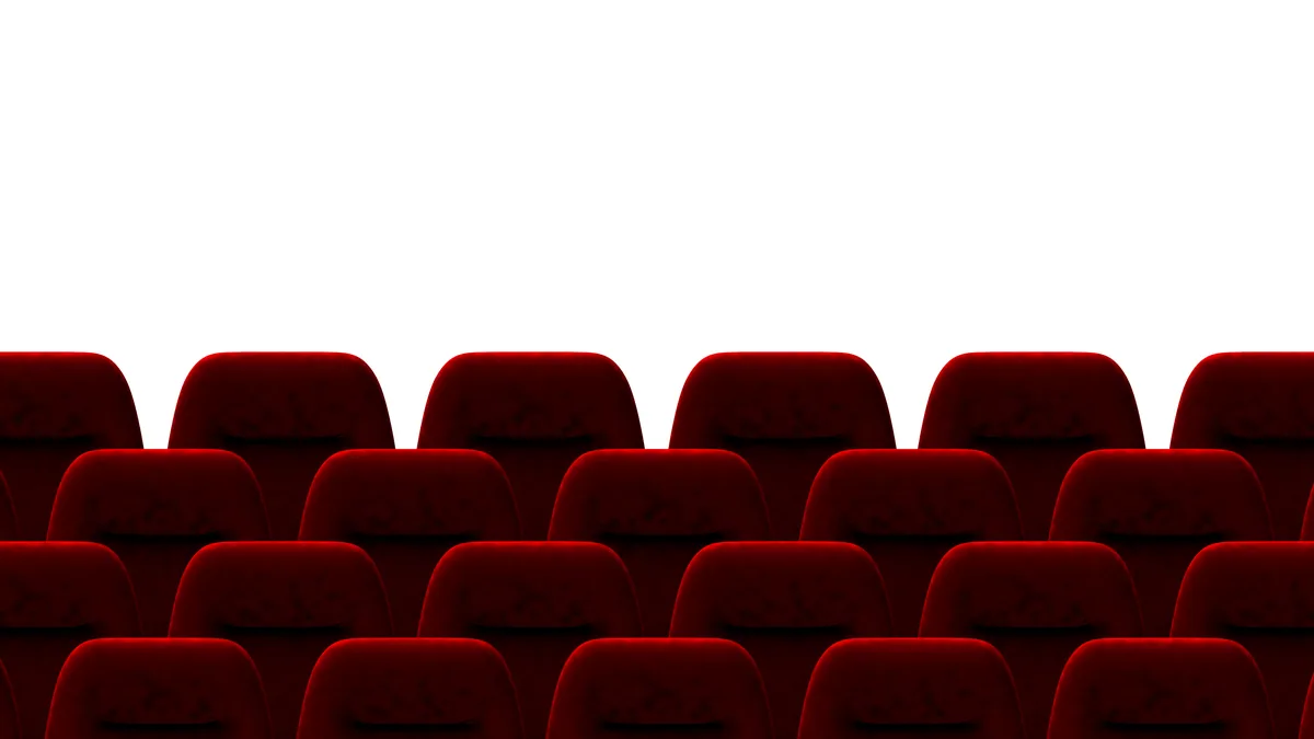 Rows of empty red cinema seats under a low ceiling glow.