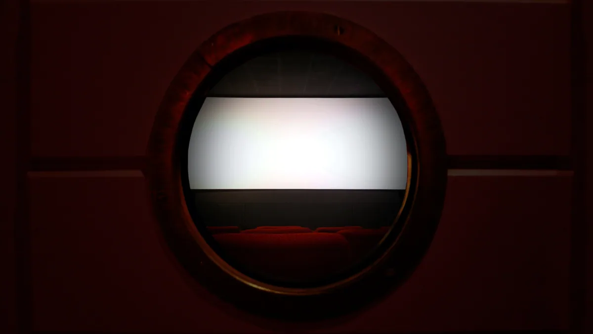 A 16mm projector casting a flickering square of light on a door.